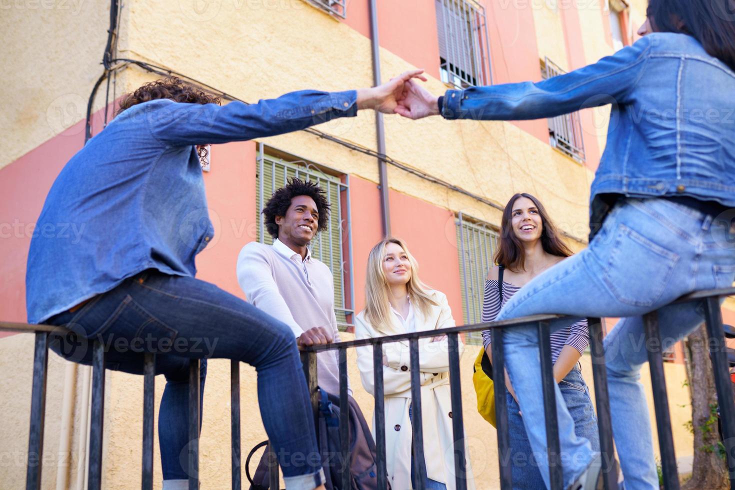 grupo multiétnico de amigos se reuniu na rua encostado em uma grade. foto