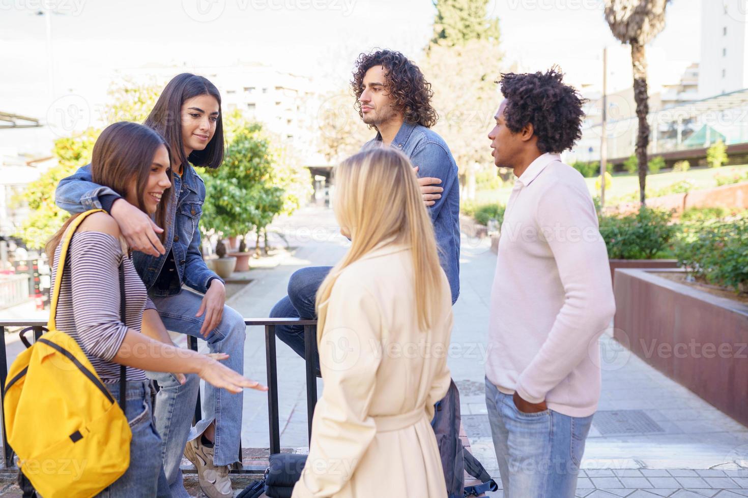 grupo multiétnico de amigos se reuniu na rua encostado em uma grade. foto