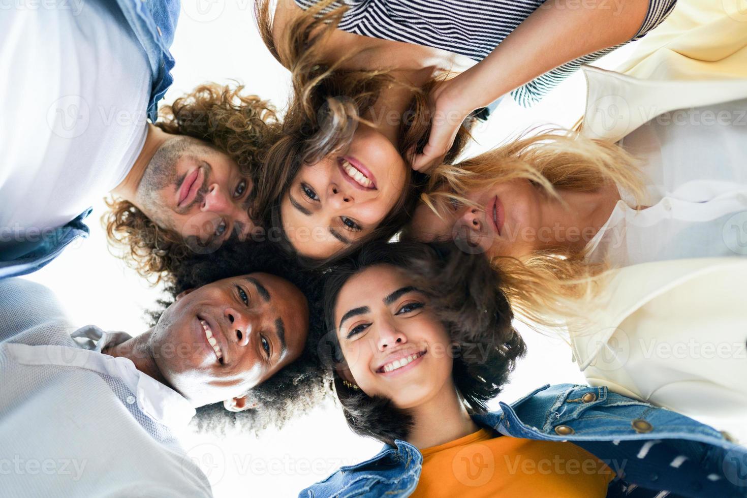 grupo multiétnico de amigos com as cabeças juntas em um círculo. foto