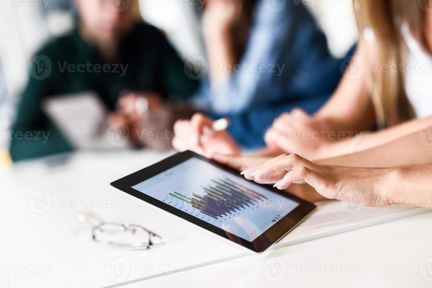 grupo de rapazes e mulheres em parceria com o computador tablet foto