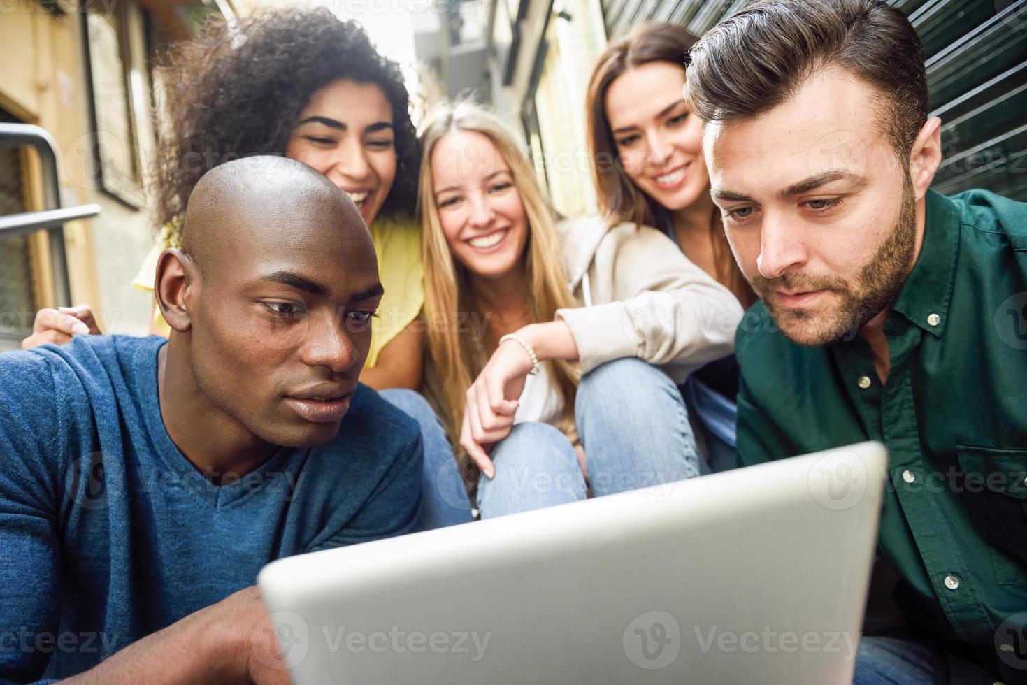 grupo multiétnico de jovens olhando para um computador tablet foto