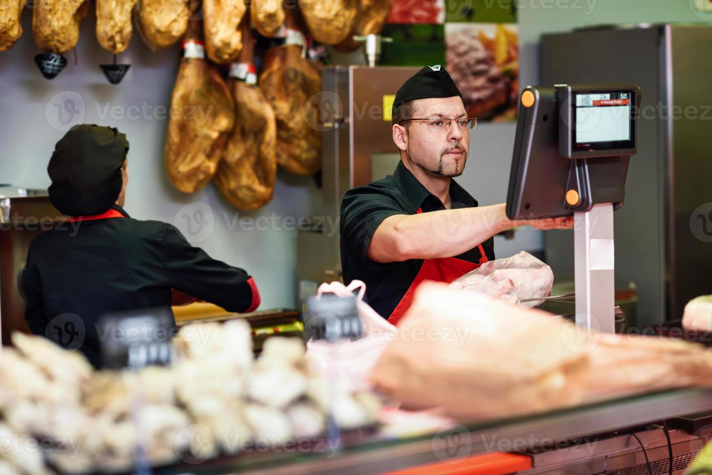 açougueiro em um açougue pesando a carne e cobrando foto