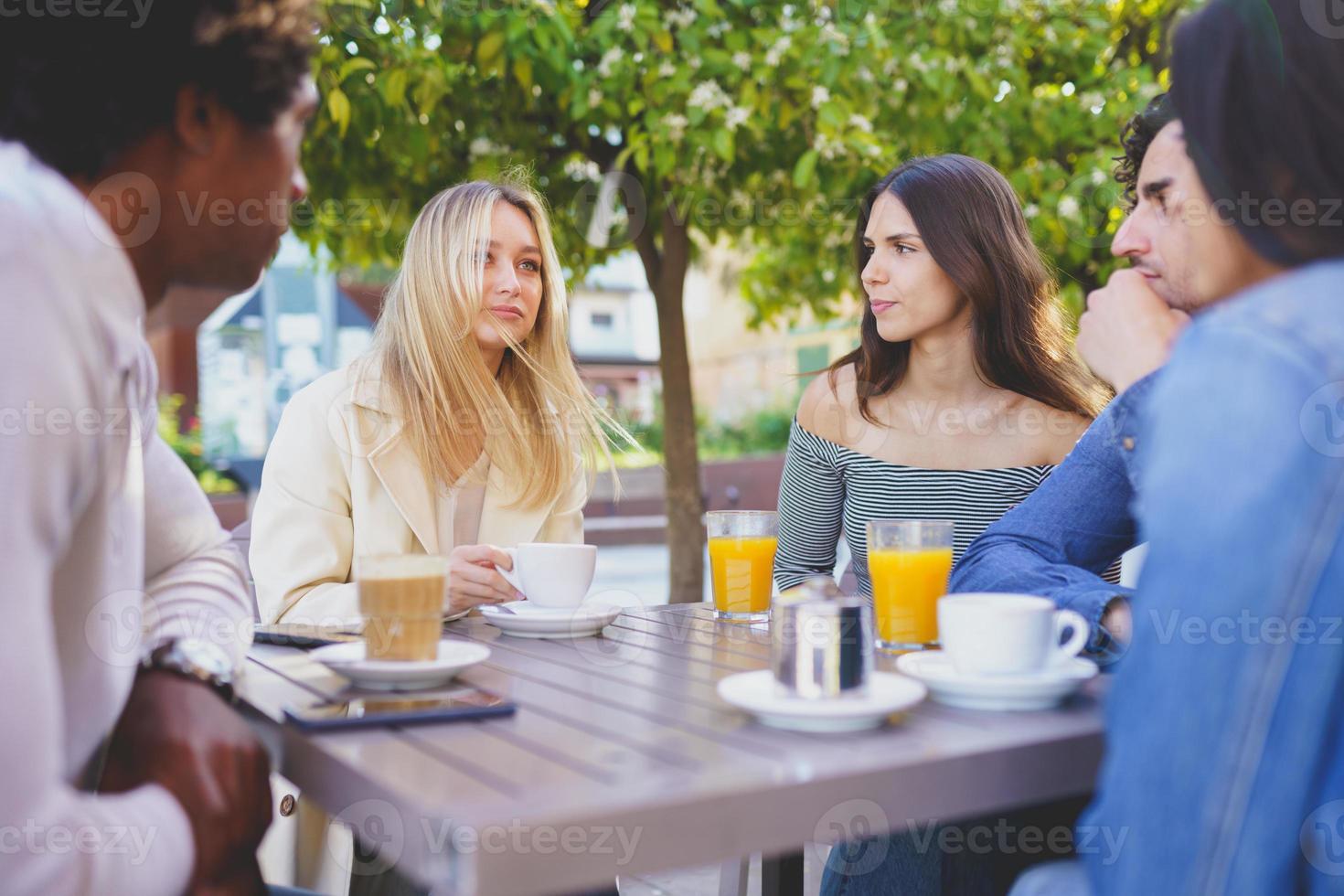 grupo multiétnico de amigos tomando uma bebida juntos em um bar ao ar livre. foto