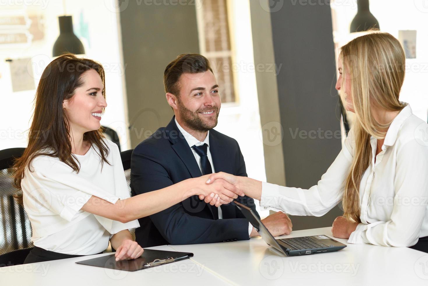 jovem casal sorridente cumprimentando um agente de seguros foto