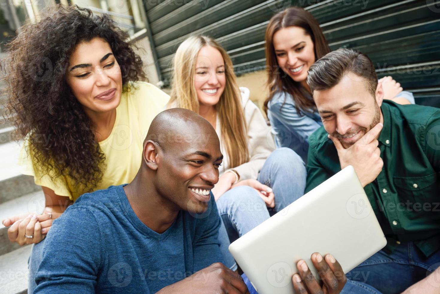 grupo multiétnico de jovens olhando para um computador tablet foto