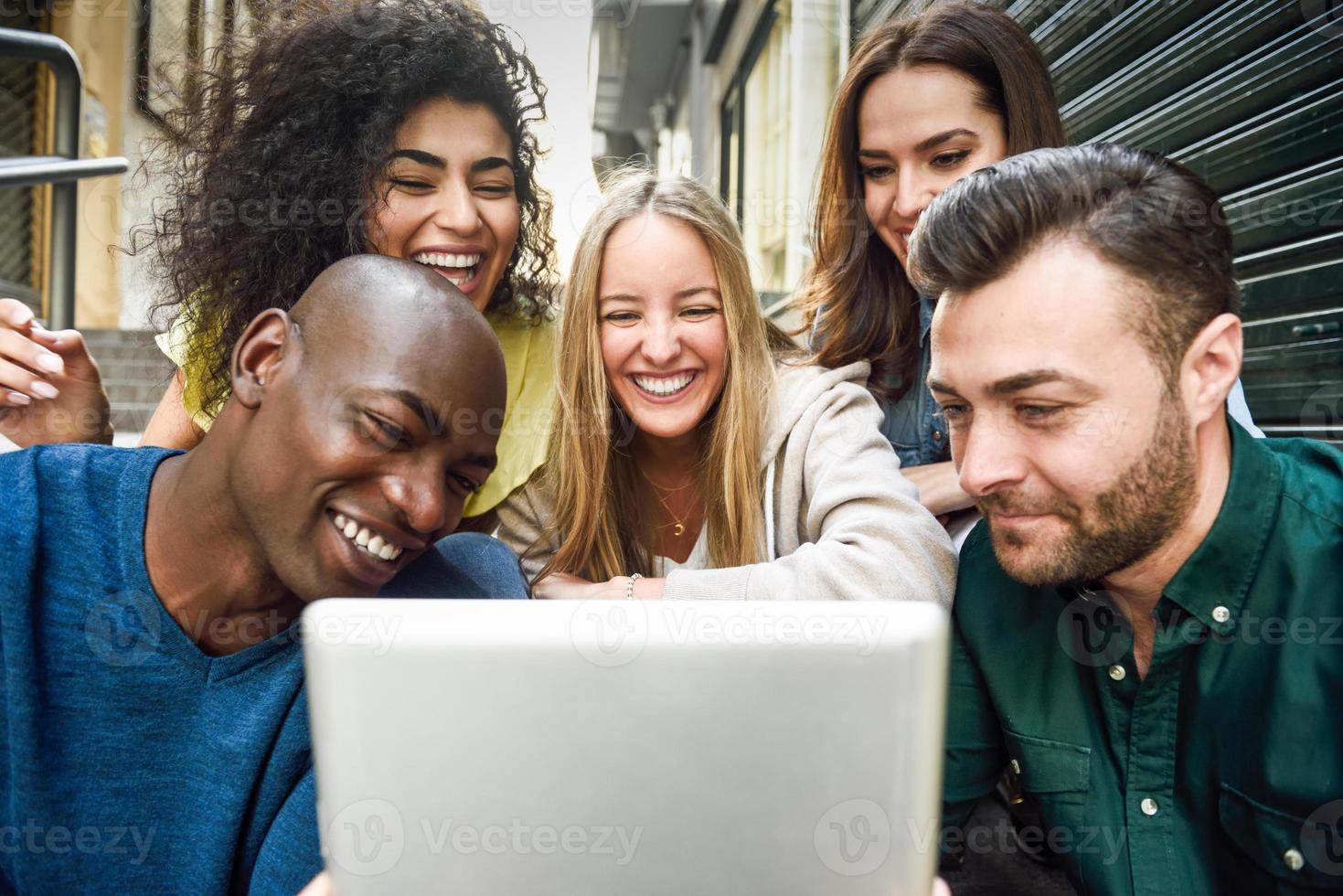 grupo multiétnico de jovens olhando para um computador tablet foto