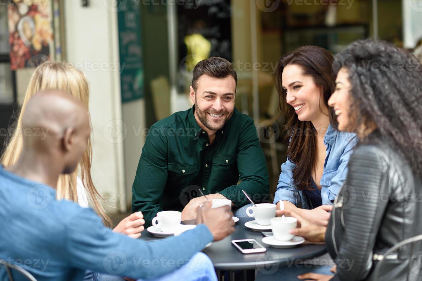 grupo multirracial de cinco amigos tomando um café juntos foto