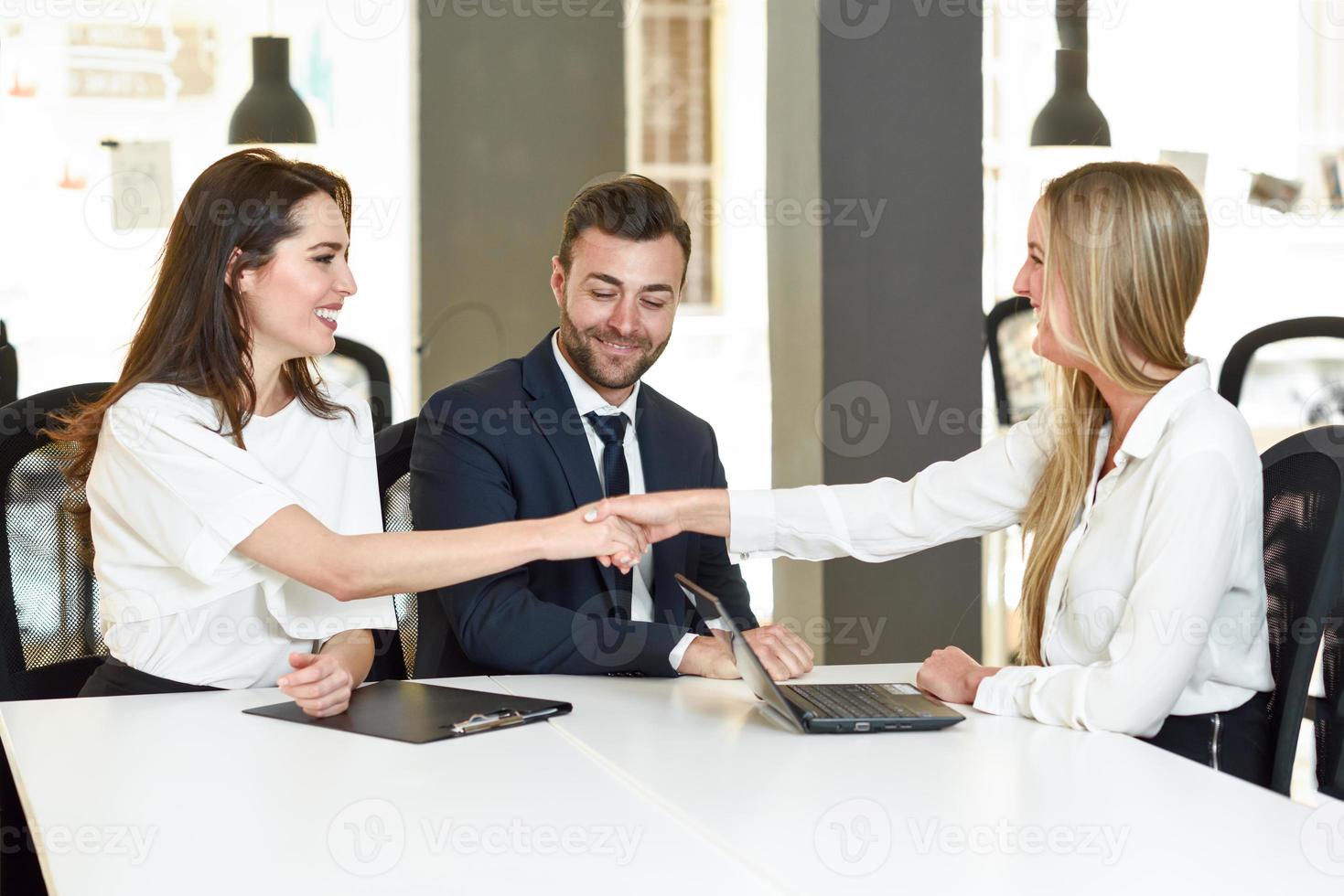 jovem casal sorridente cumprimentando um agente de seguros foto