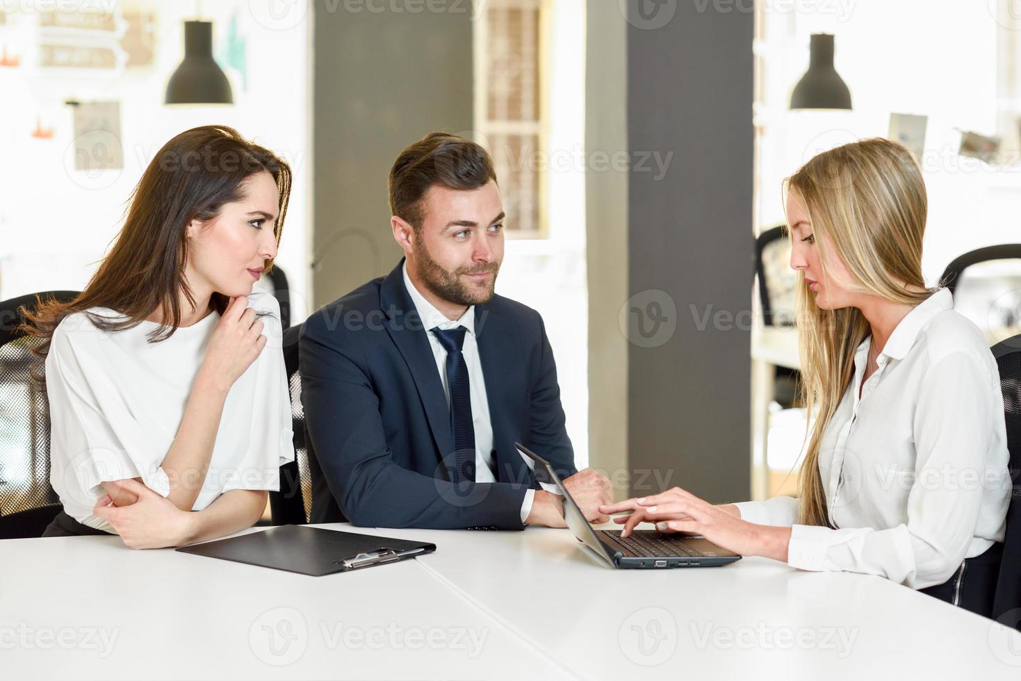 loira empresária explicando com o laptop para o jovem casal sorridente. foto