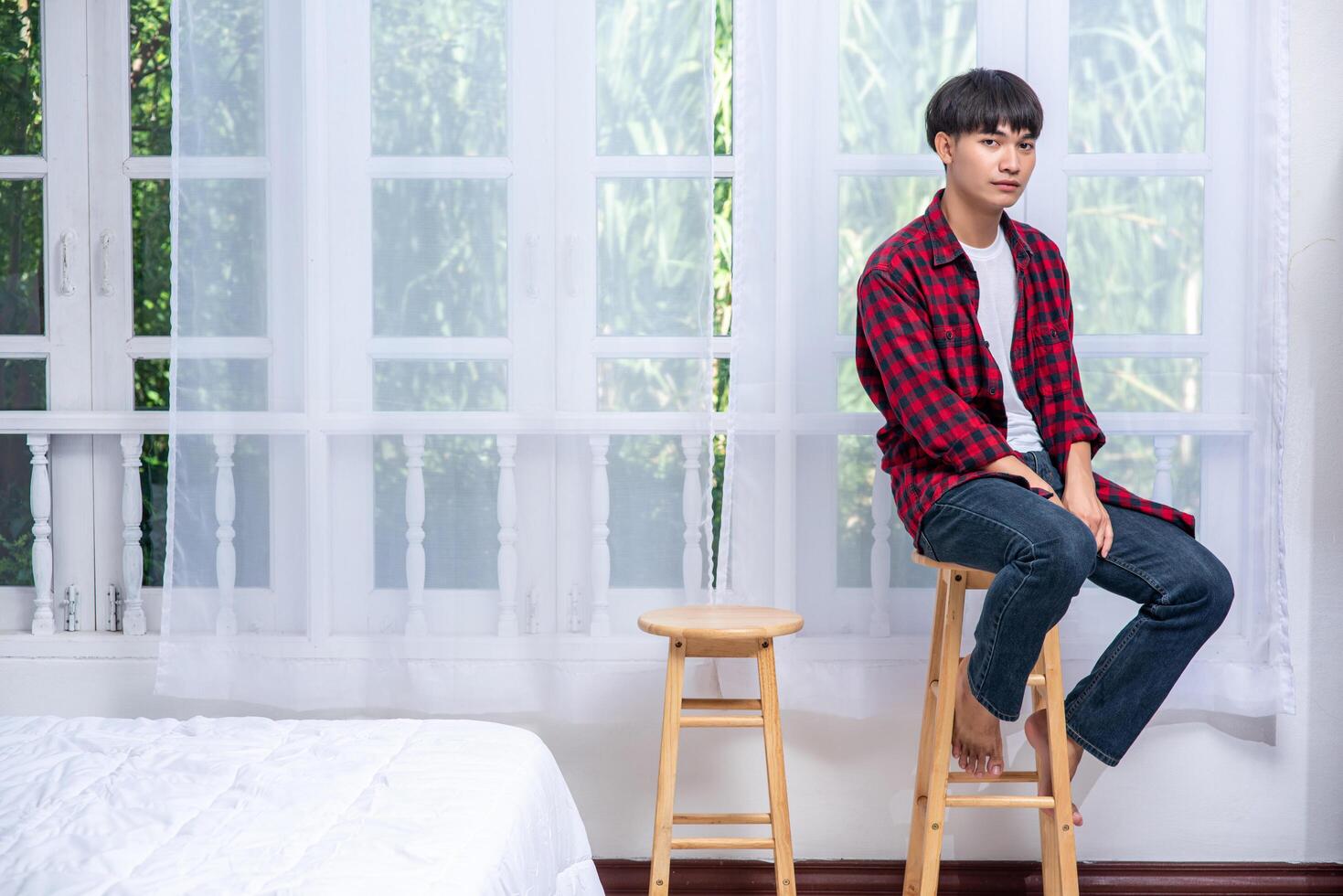 um jovem com uma camisa listrada está sentado em uma cadeira alta. foto