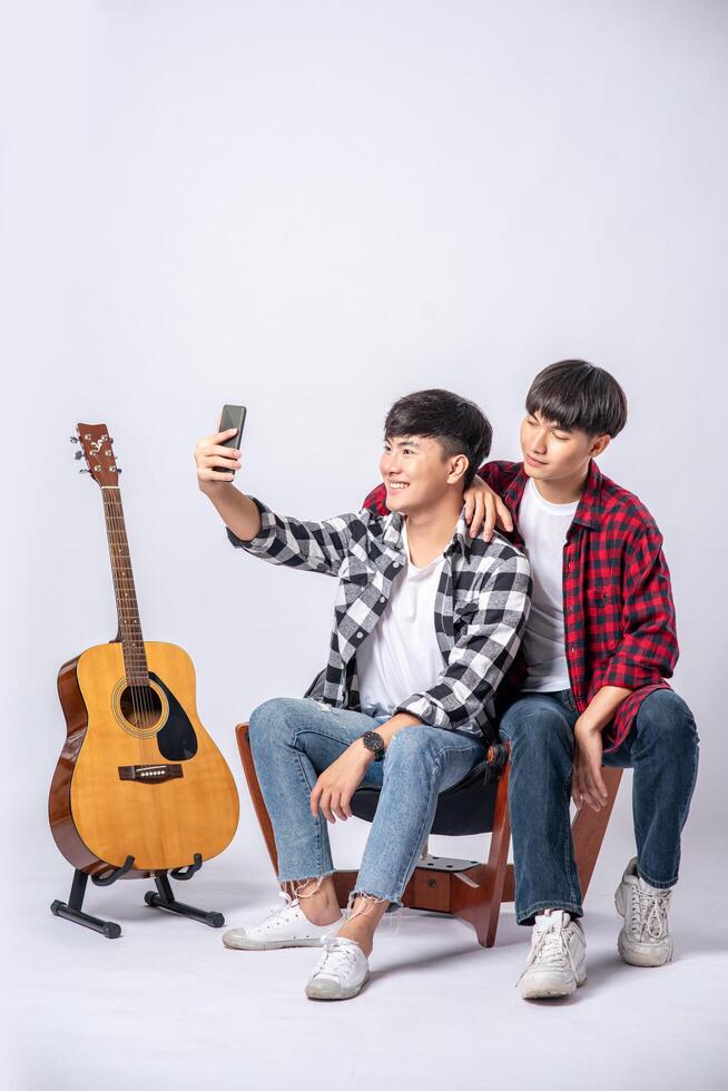dois amáveis jovens se sentam em uma cadeira e tiram uma selfie em um smartphone. foto