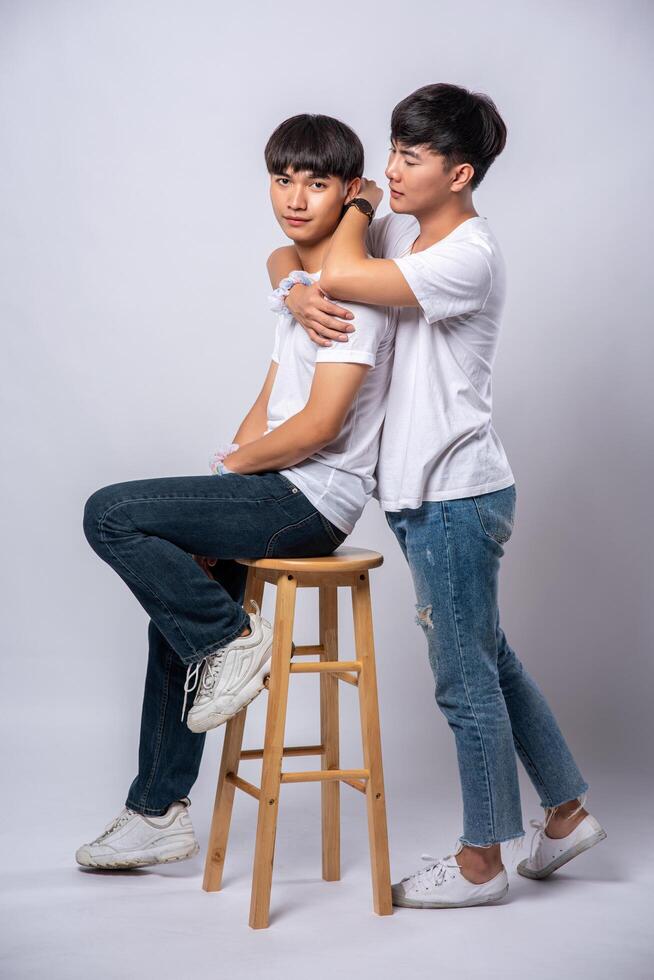 dois homens que se amam se abraçam e sentam em uma cadeira. foto
