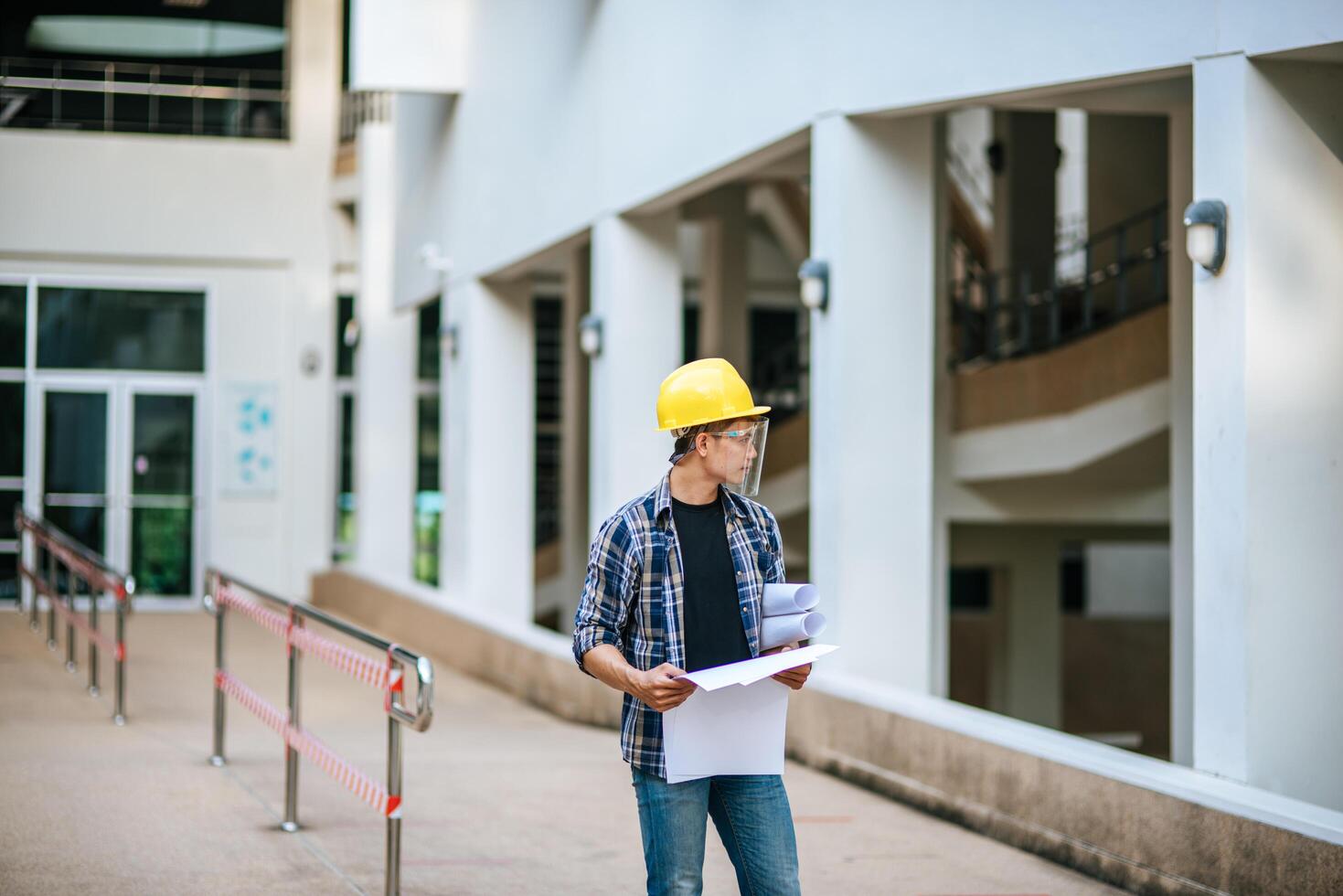 arquitetos seguram a planta do prédio e verificam a obra. foto