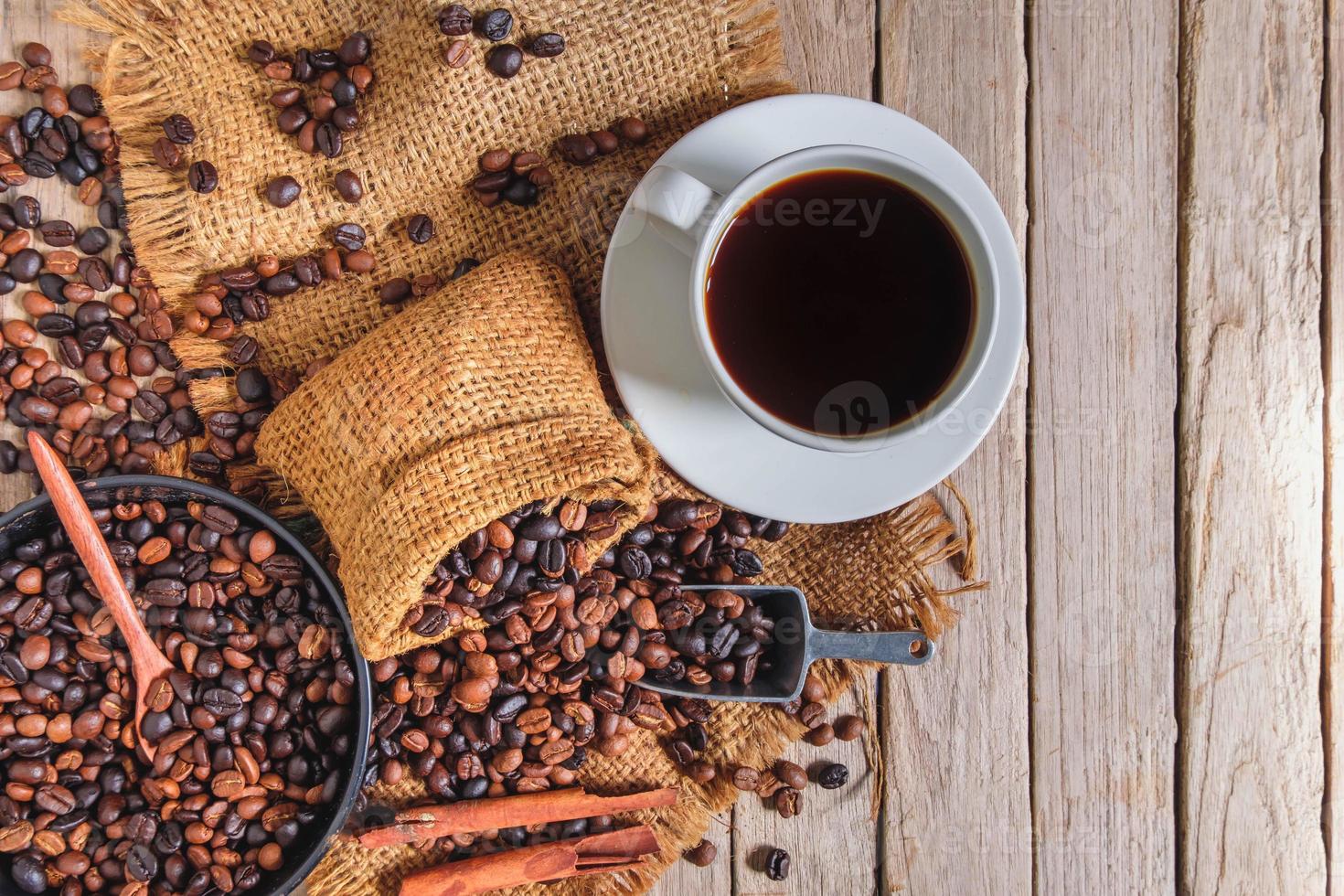 xícara de café e grãos na velha mesa de madeira foto