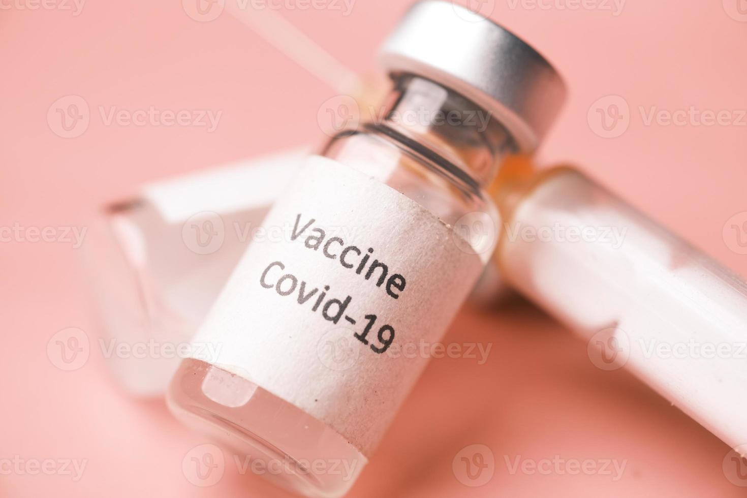 close-up de vacina de coronavírus e seringa em fundo rosa foto