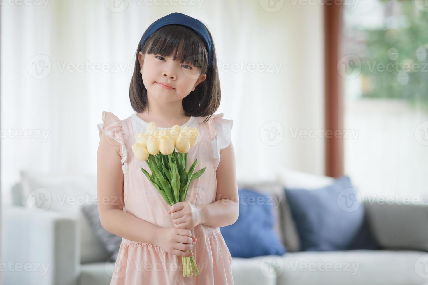 retrato de flor de holdign menina bonita asiática com sorriso encantador feliz na sala de estar em casa. foto