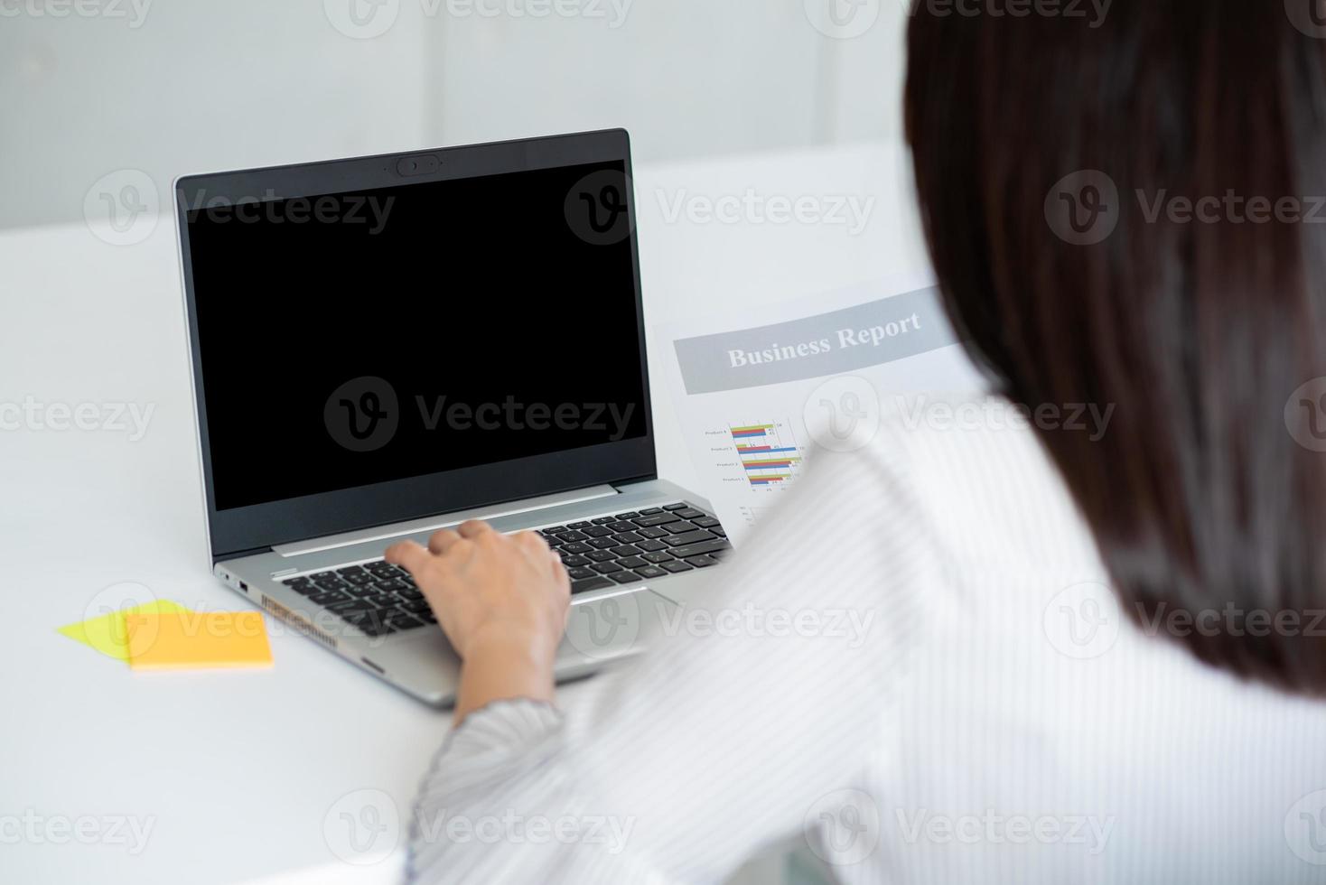 vista traseira da mulher de negócios usando laptop com tela preta no escritório. projeto da foto com espaço de cópia para mock up para o conceito de negócio