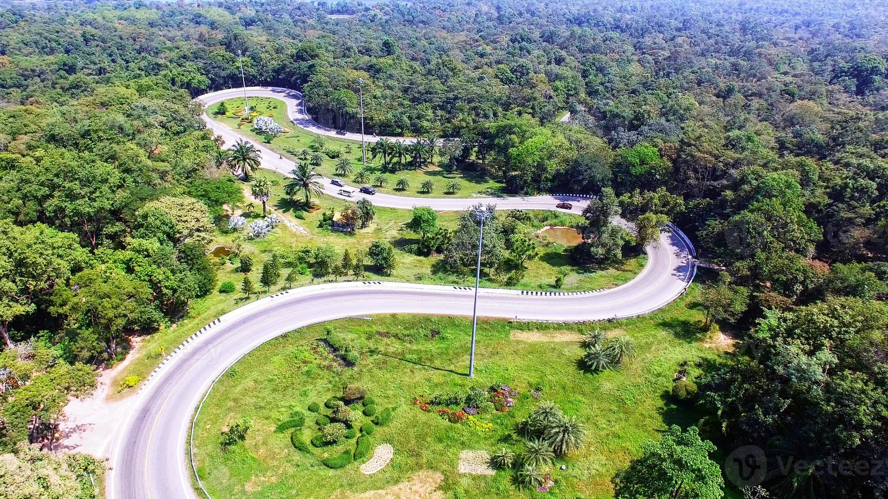 vista aérea do drone de carros está passando por uma estrada de curva na montanha com floresta verde. a estrada de transporte através da montanha. foto