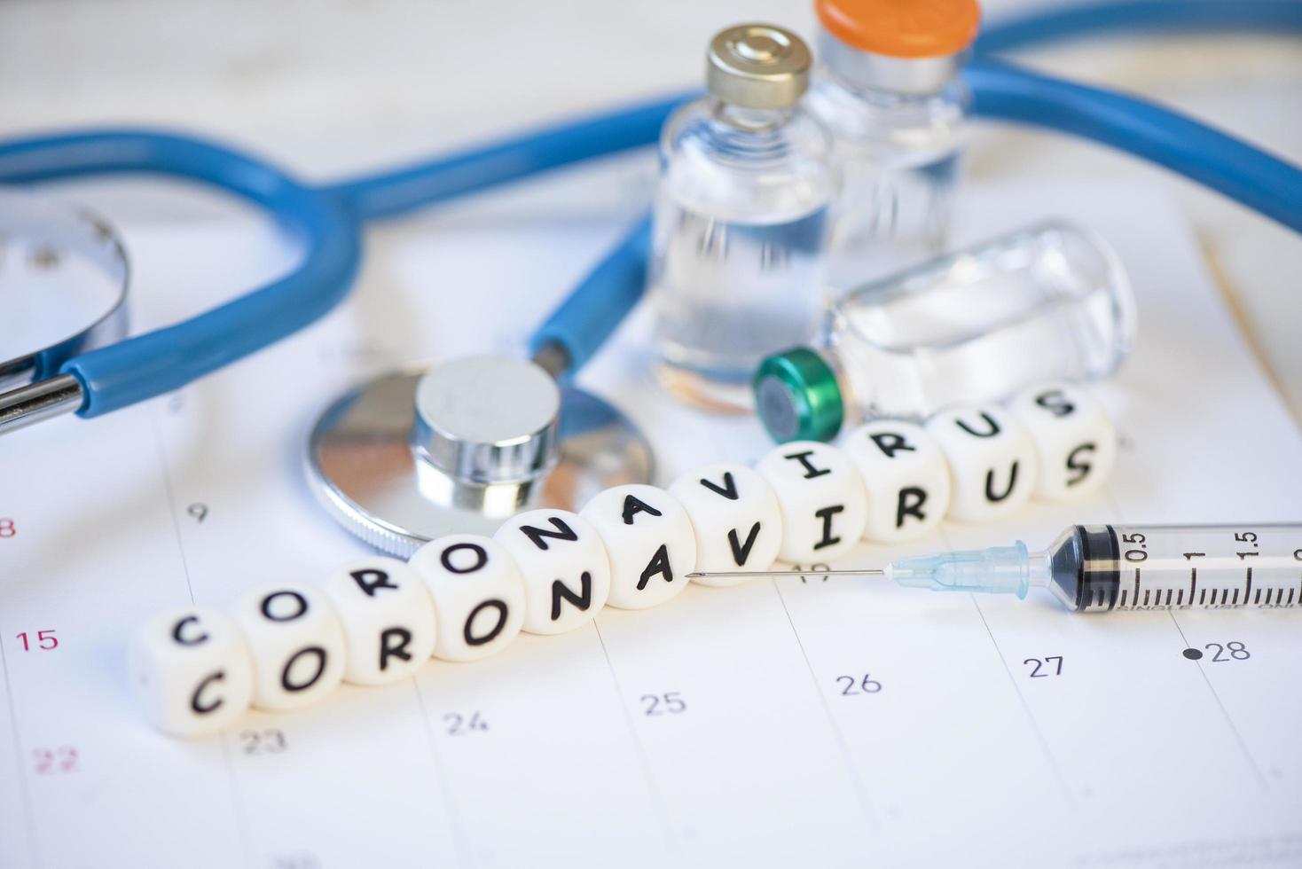 vacina de coronavírus com medicamento de injeção de seringa e estetoscópio no frasco de vacina de calendário para covid-19 prevenção de risco de saúde pública pandêmica de crise médica de influenza disseminada por coronavírus covid-19 foto