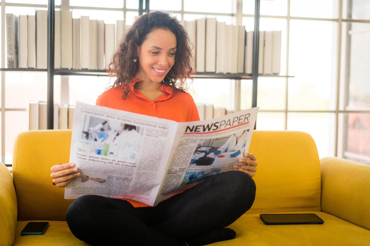 mulher da américa latina lendo jornal no sofá foto