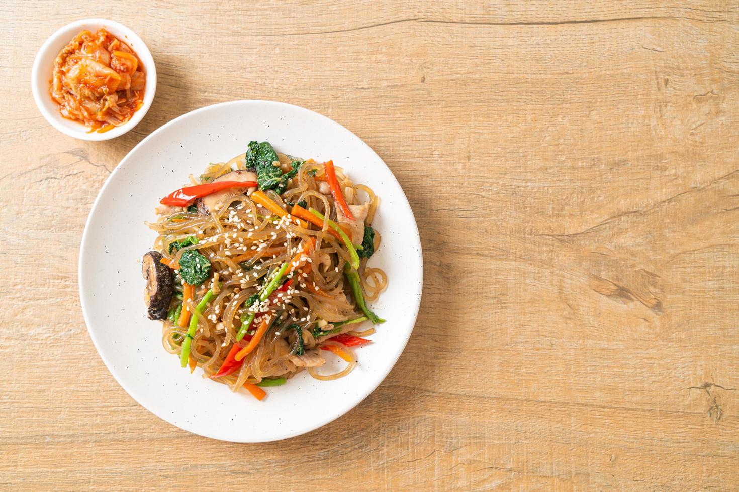 macarrão macarrão coreano japonês ou refogado com legumes e carne de porco coberta com gergelim branco foto