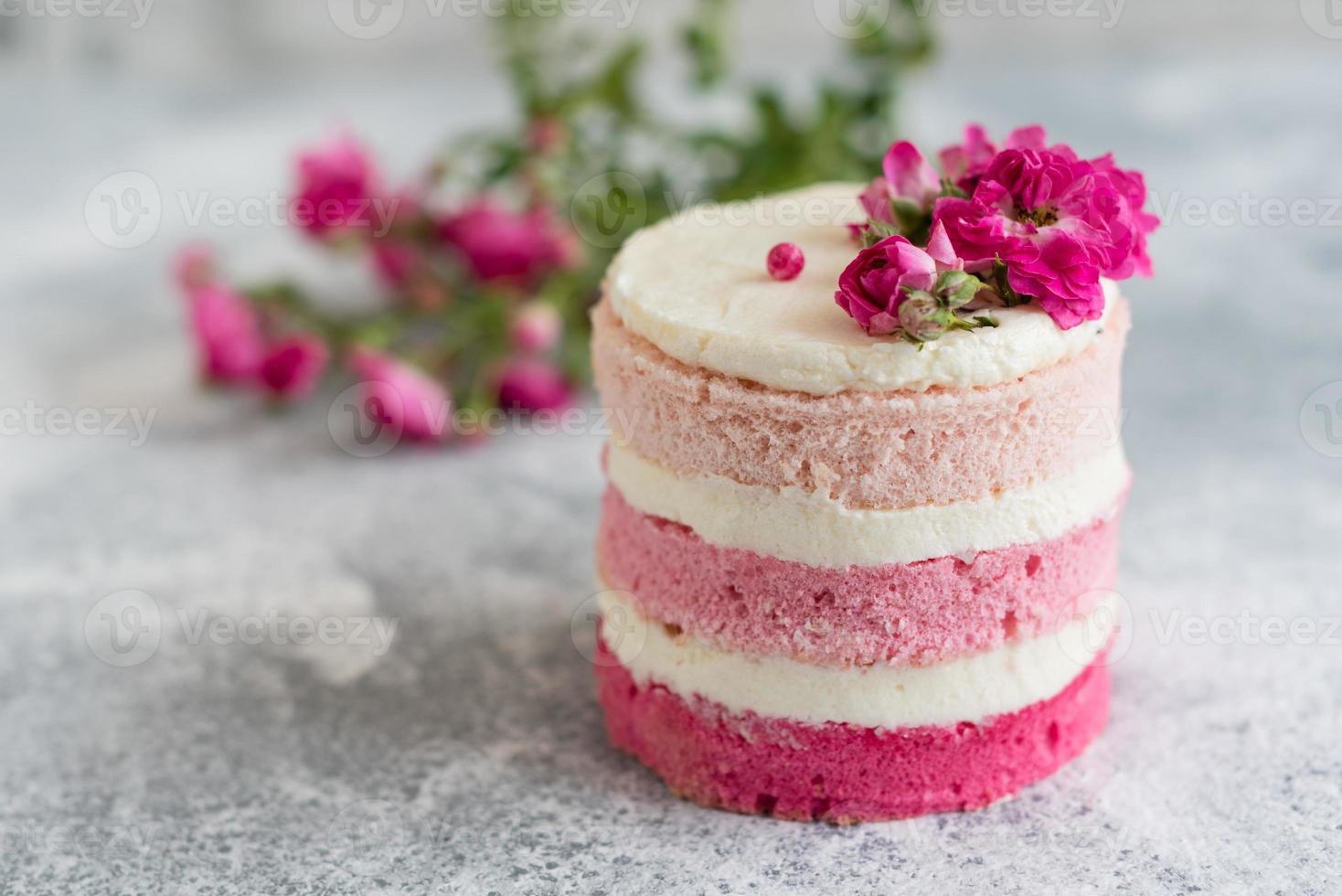 um pequeno bolo de branco e rosa decorado com flores e frutos silvestres foto