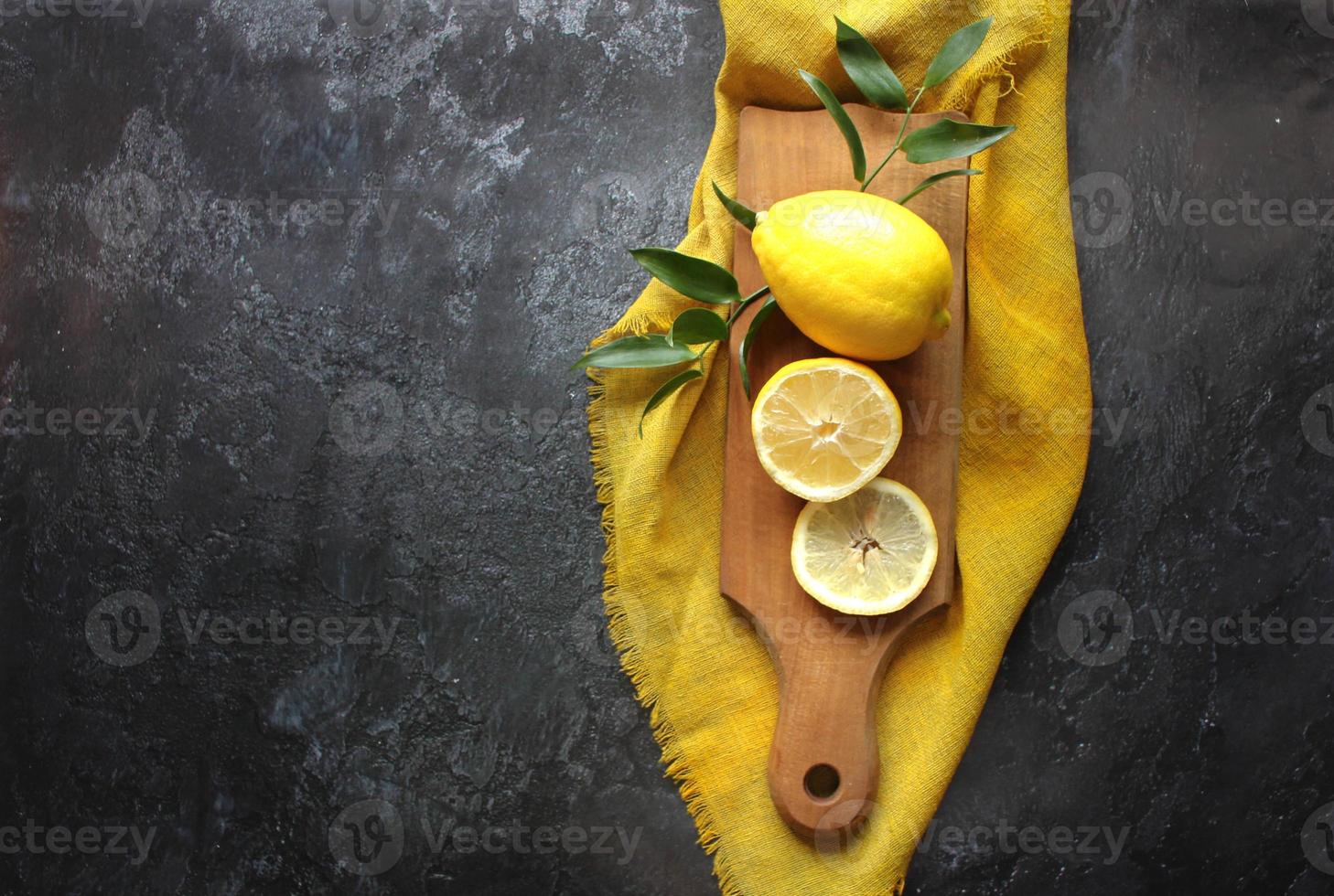 limões e folhas verdes em fundo preto brilhante. vista superior plana lay cópia espaço. limão frutas cítricas conceito mínimo vitamina c. foto