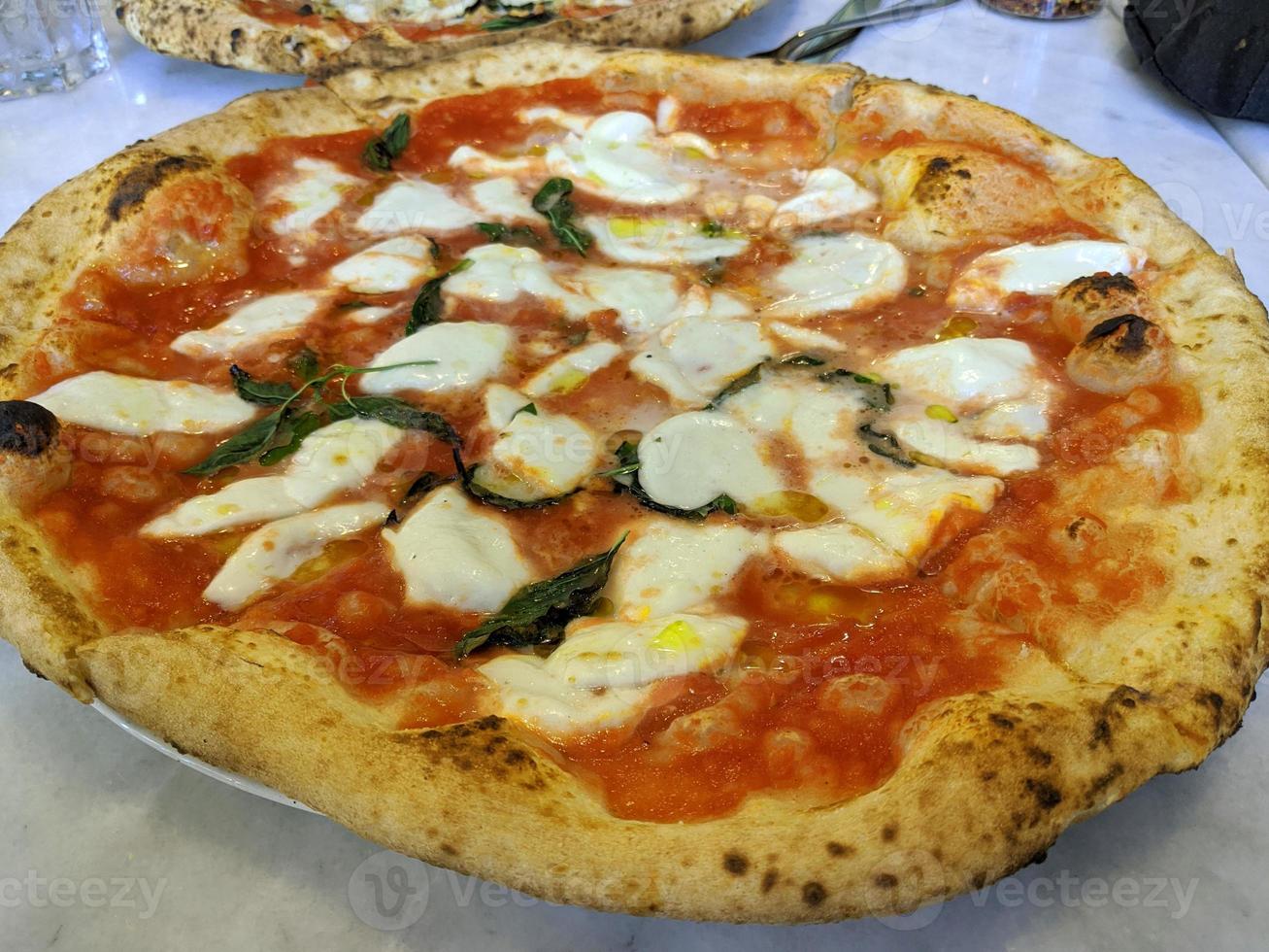 pizza saborosa pimenta calabresa coberta de fatias de tomate cozinhar ingredientes com presunto e especiarias vermelhas de tomate na mesa. foto