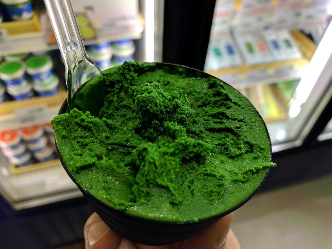 padrão de sobremesa congelada de sabor verde de sorvete na mão de copo preto segurando na madeira. foto