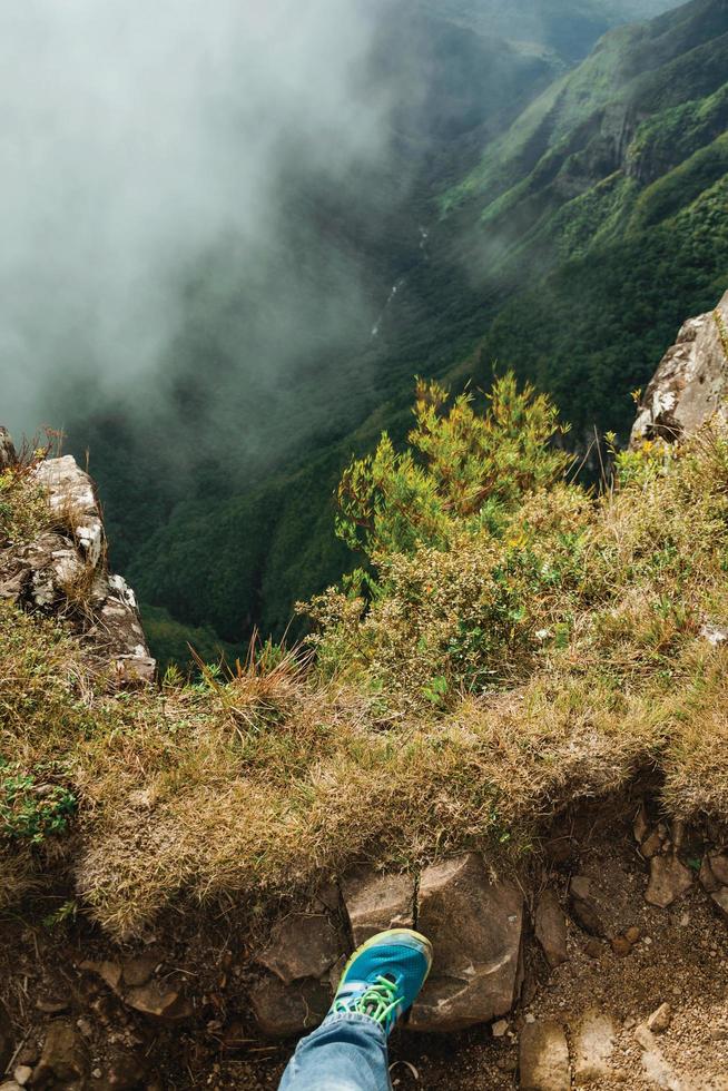 pé sobre a rocha à beira de profundos penhascos rochosos com neblina no cânion de fortaleza próximo a cambara do sul. uma pequena cidade do sul do Brasil com incríveis atrações turísticas naturais. foto