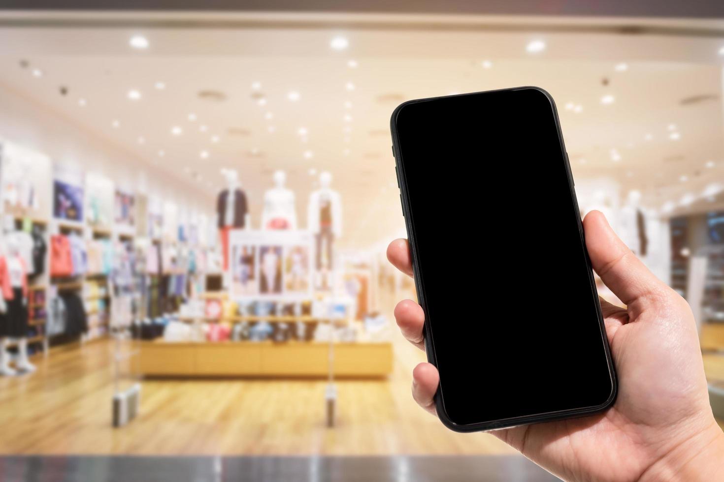 close-up de imagens desfocadas de smartphone de uso feminino no shopping e loja de roupas desfocagem do fundo. foto