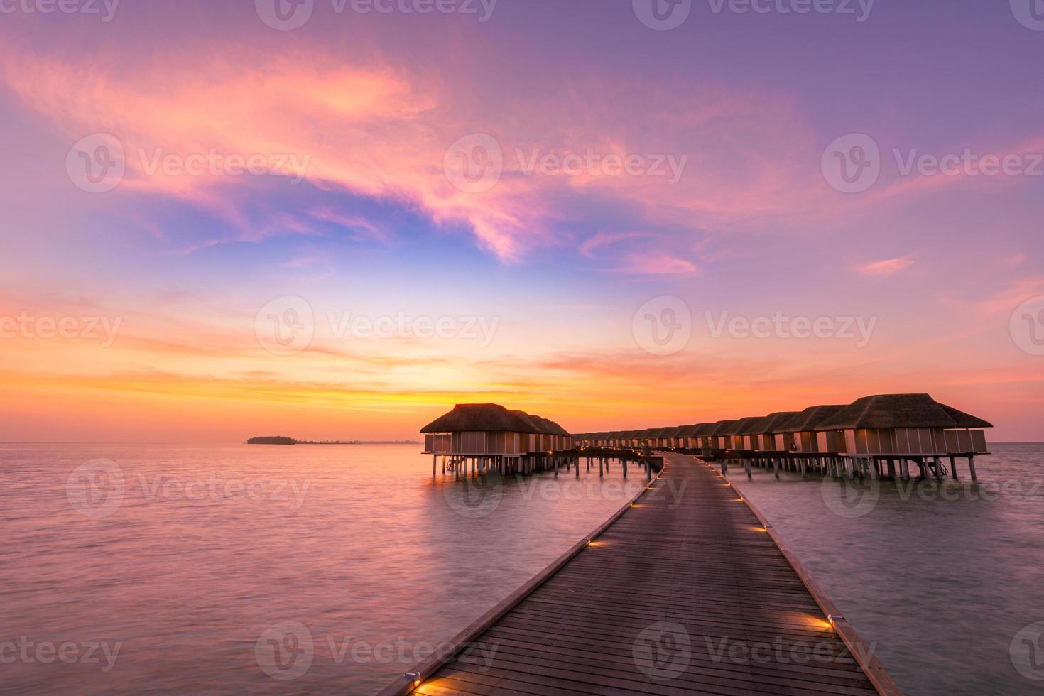 panorama incrível do pôr do sol nas maldivas. luxo resort vilas vista do mar com luzes LED suaves sob o céu colorido. lindo céu crepuscular e nuvens coloridas. fundo de praia lindo para férias de férias foto