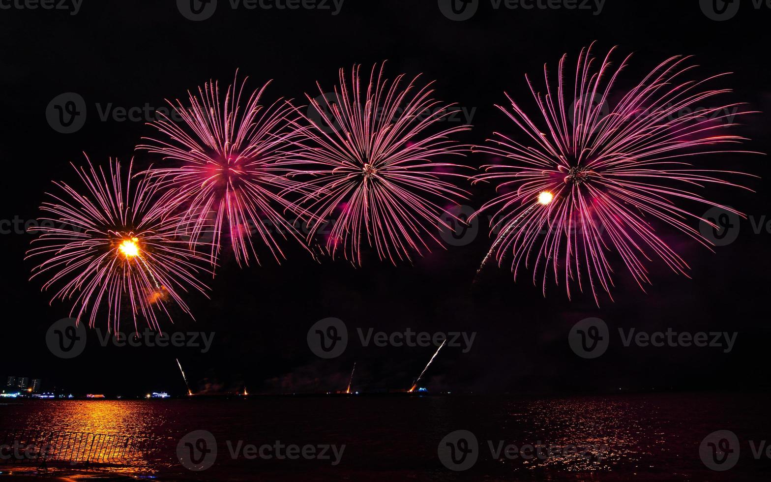 incríveis e lindos fogos de artifício coloridos na noite de celebração, mostrando na praia do mar com reflexo de várias cores na água foto