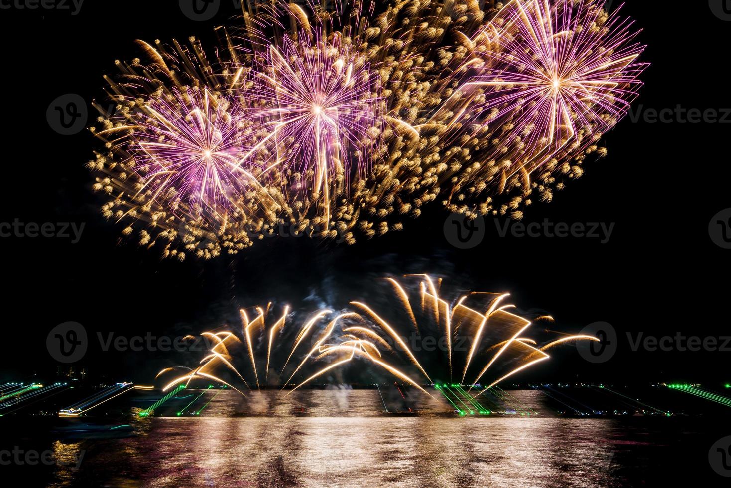 incríveis e lindos fogos de artifício coloridos na noite de celebração, mostrando na praia do mar com reflexo de várias cores na água foto