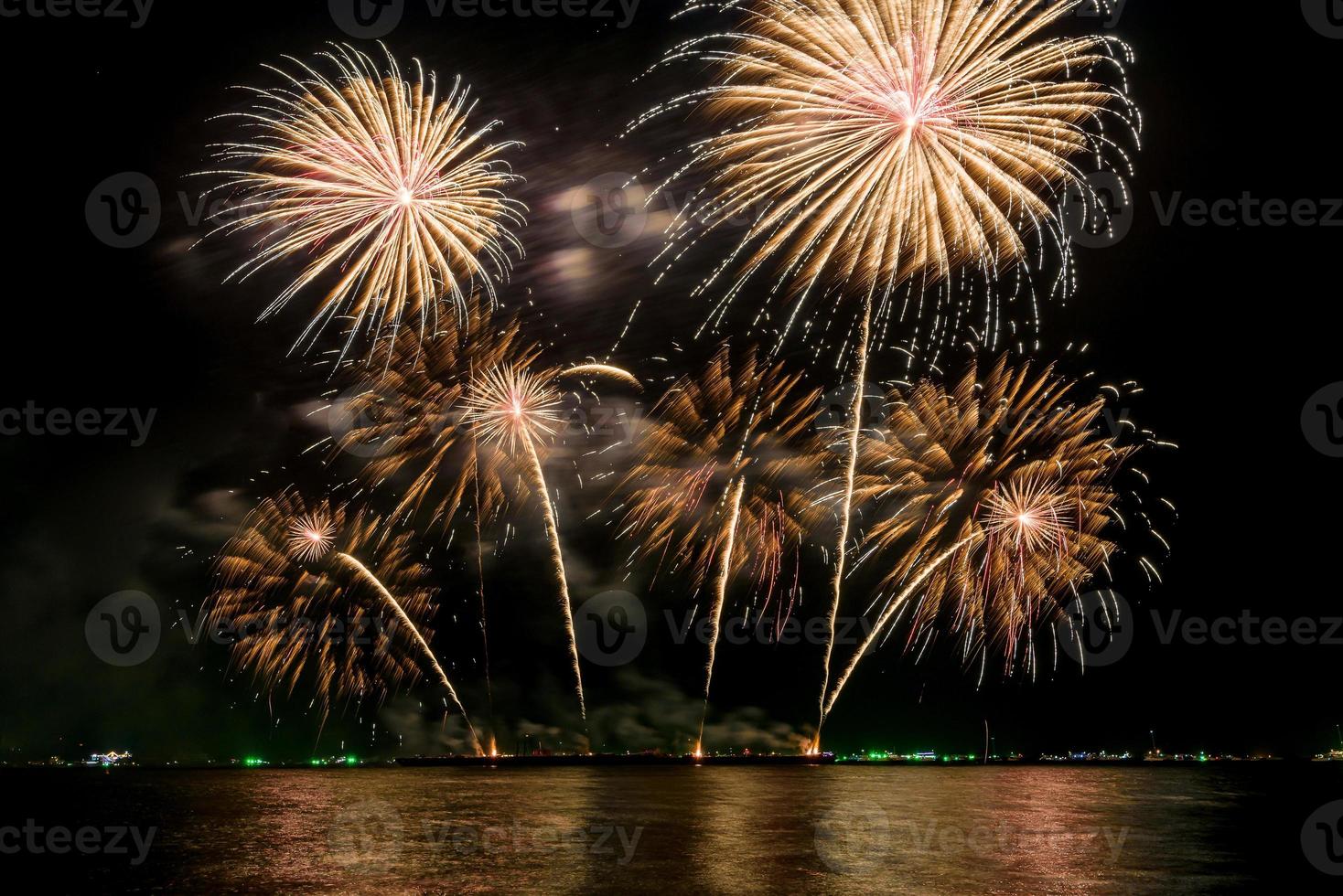 incríveis e lindos fogos de artifício coloridos na noite de celebração, mostrando na praia do mar com reflexo de várias cores na água foto