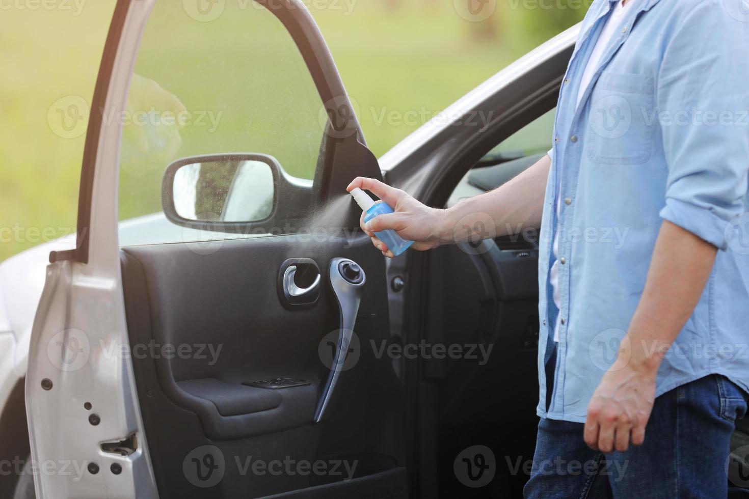 pulverizando spray desinfetante antibacteriano no carro do volante, conceito de controle de infecção. prevenir coronavírus, covid-19, gripe. homem usando máscara protetora médica, dirigindo um carro. toalhetes desinfetantes. foto