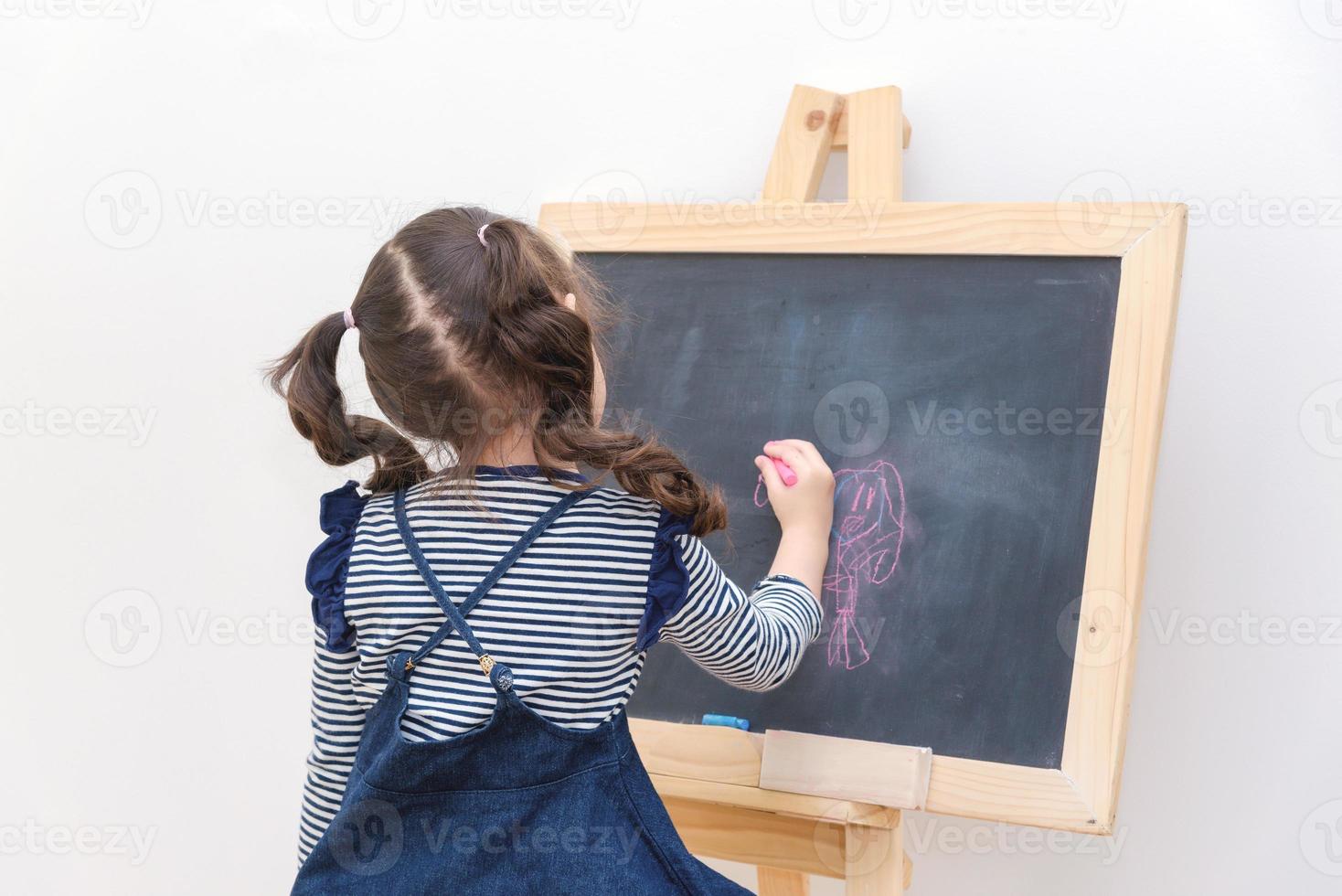 criança feliz menina asiática desenhar desenhos animados com giz na lousa para aprender em casa. foto para a educação infantil e o conceito de estudo escolar.