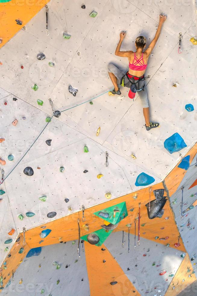 uma mulher está escalando uma parede de escalada foto