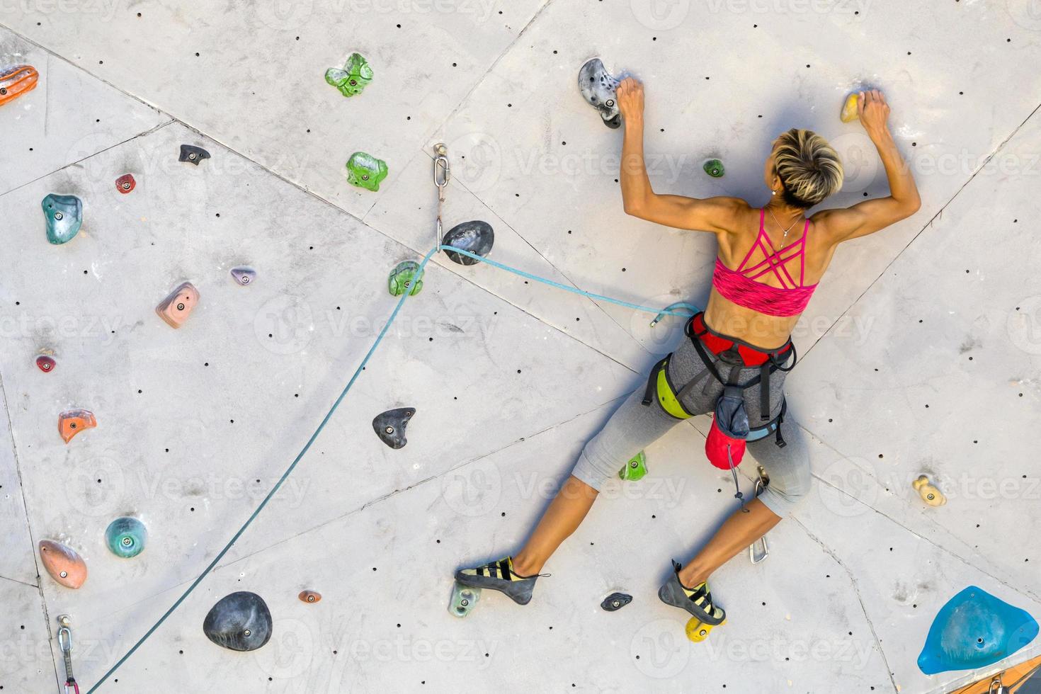 uma mulher está escalando uma parede de escalada foto