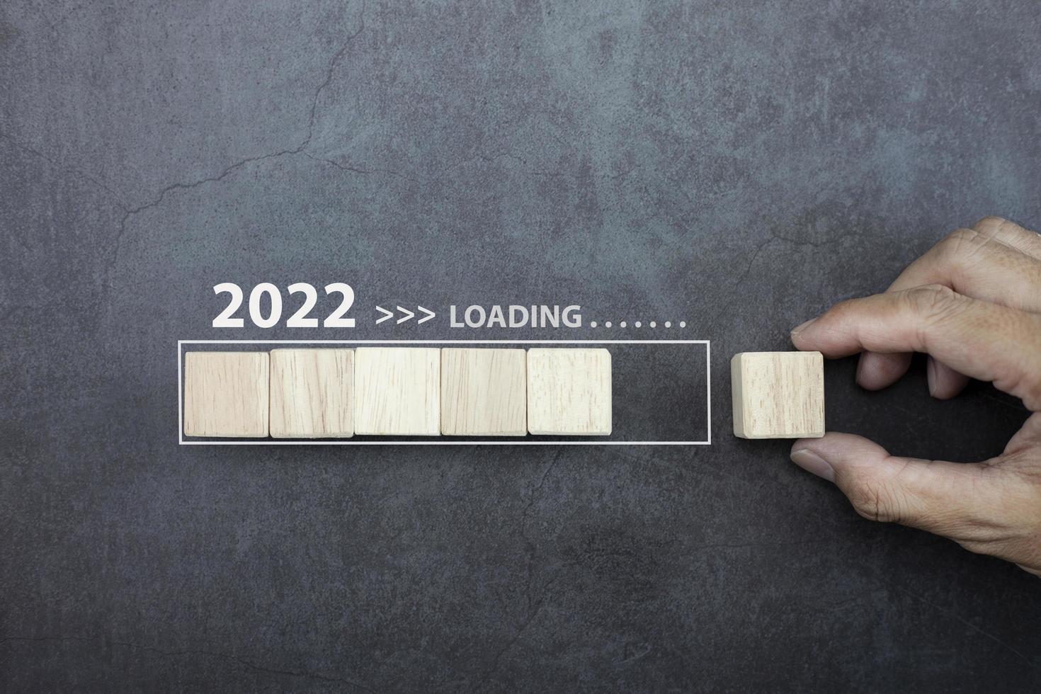 carregando o conceito de ano novo 2022, homem de mão colocando o cubo de madeira na barra de processo. foto