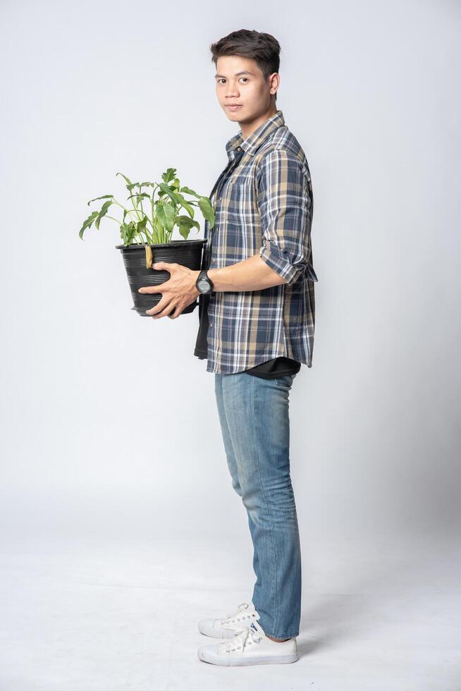 um homem se levantou e segurou um vaso de planta em sua casa. foto