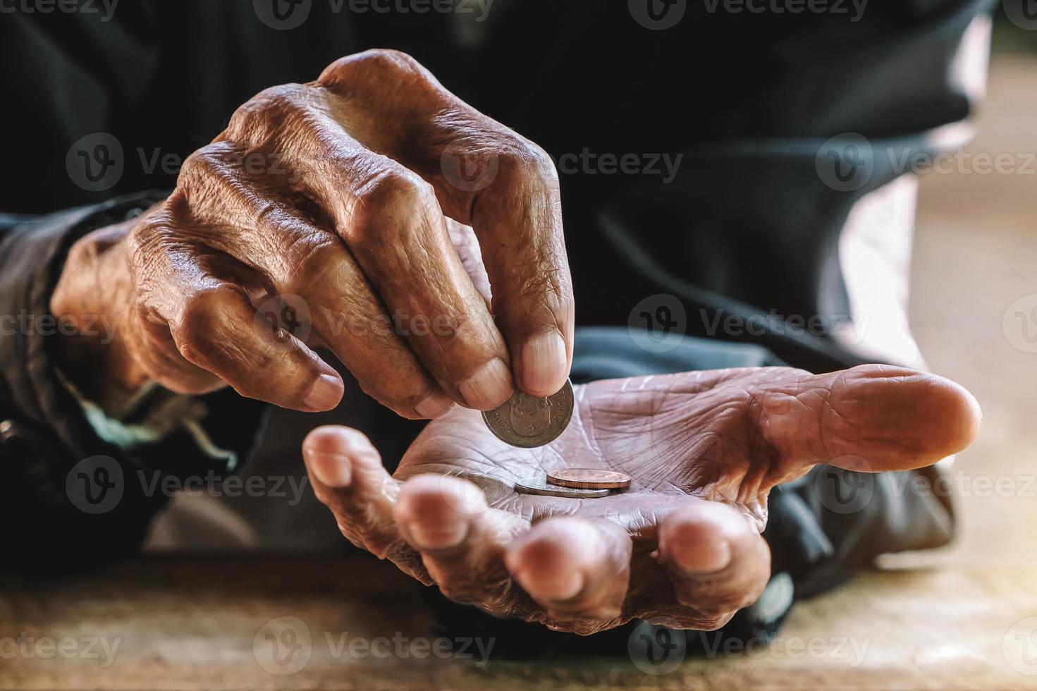 mão velho implorando por dinheiro por causa da fome na mesa de madeira. tom vintage foto