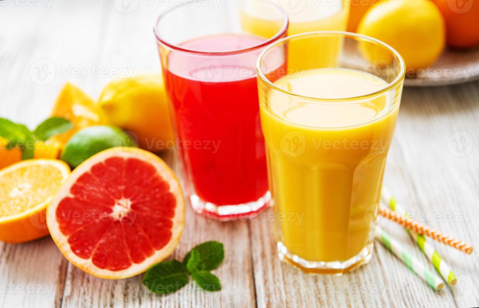 copos de suco e frutas cítricas foto