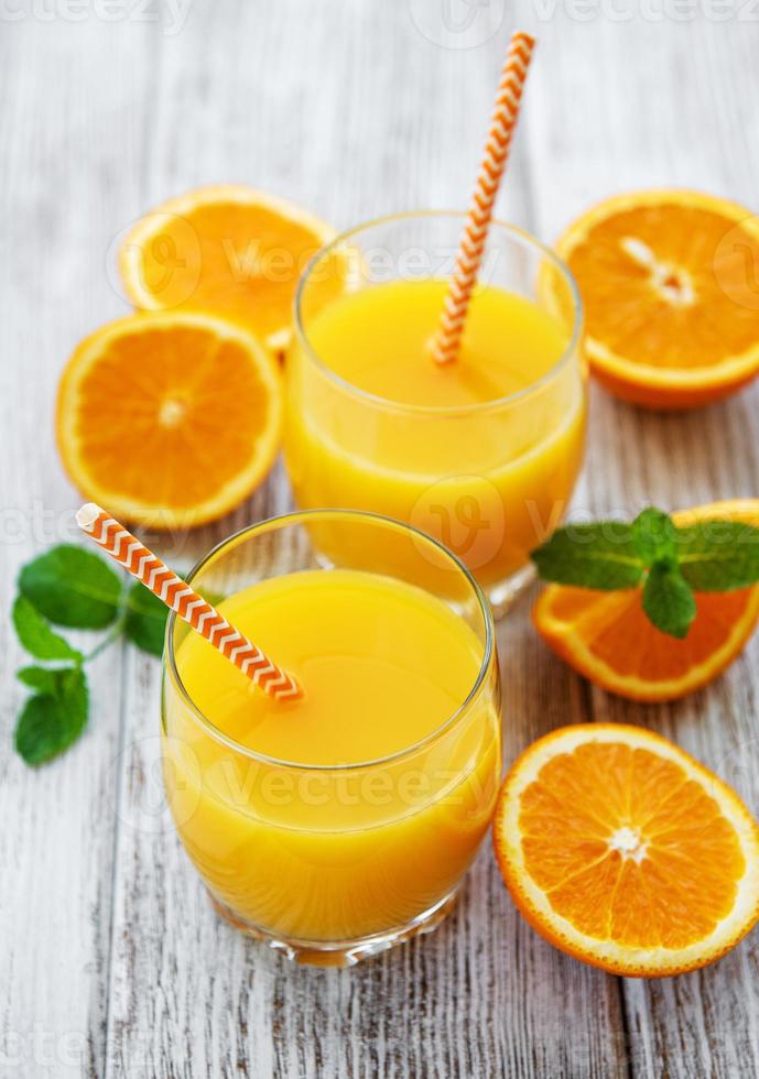 copos de suco e frutas de laranja foto