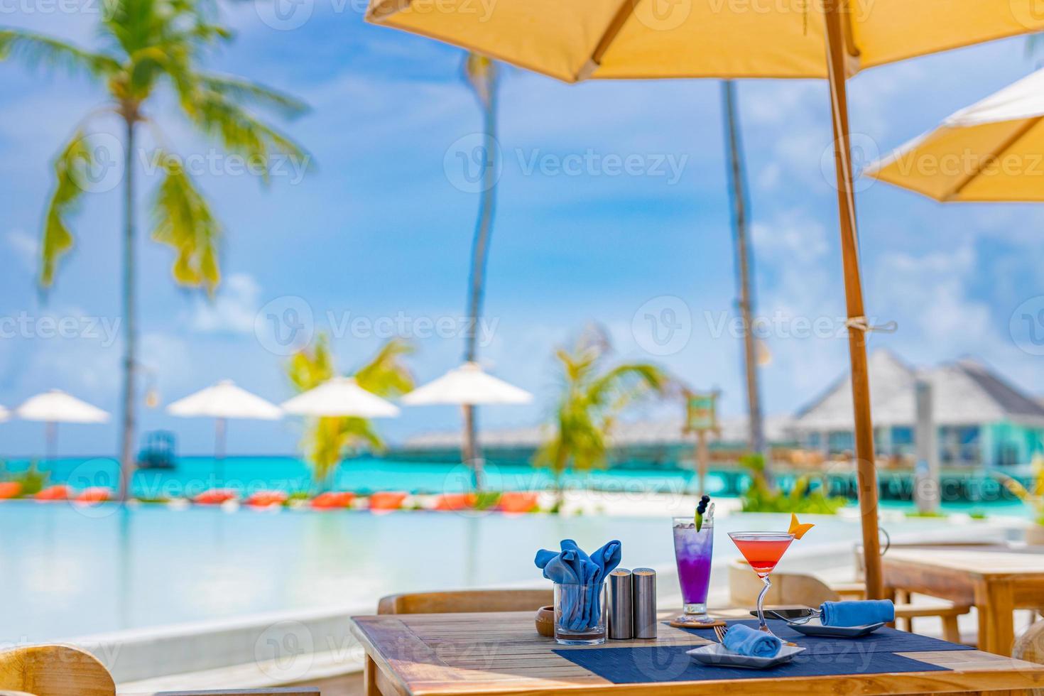 hotel resort de luxo à beira da piscina, restaurante ao ar livre na praia, oceano e céu, café em uma ilha tropical, mesas, comida. férias ou férias de verão, viagens em família. palmeiras, piscina infinita, coquetéis, relax foto