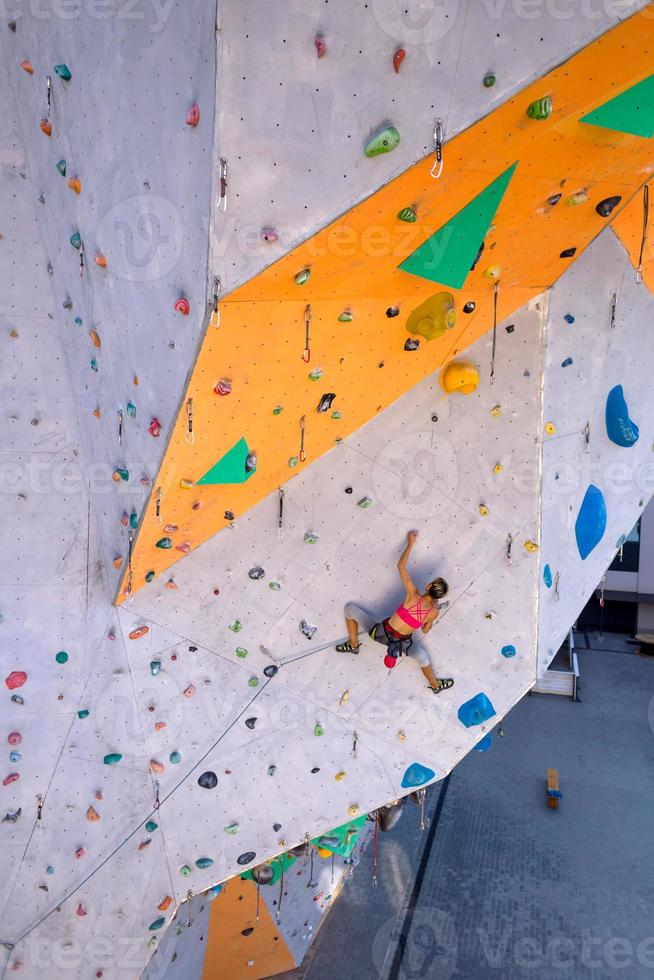 uma mulher está escalando uma parede de escalada foto