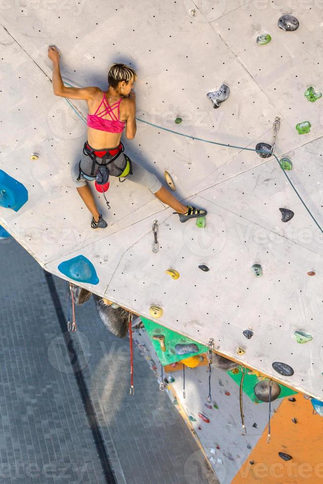 uma mulher está escalando uma parede de escalada foto