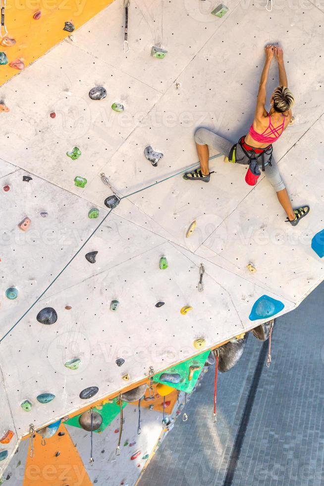 uma mulher está escalando uma parede de escalada foto