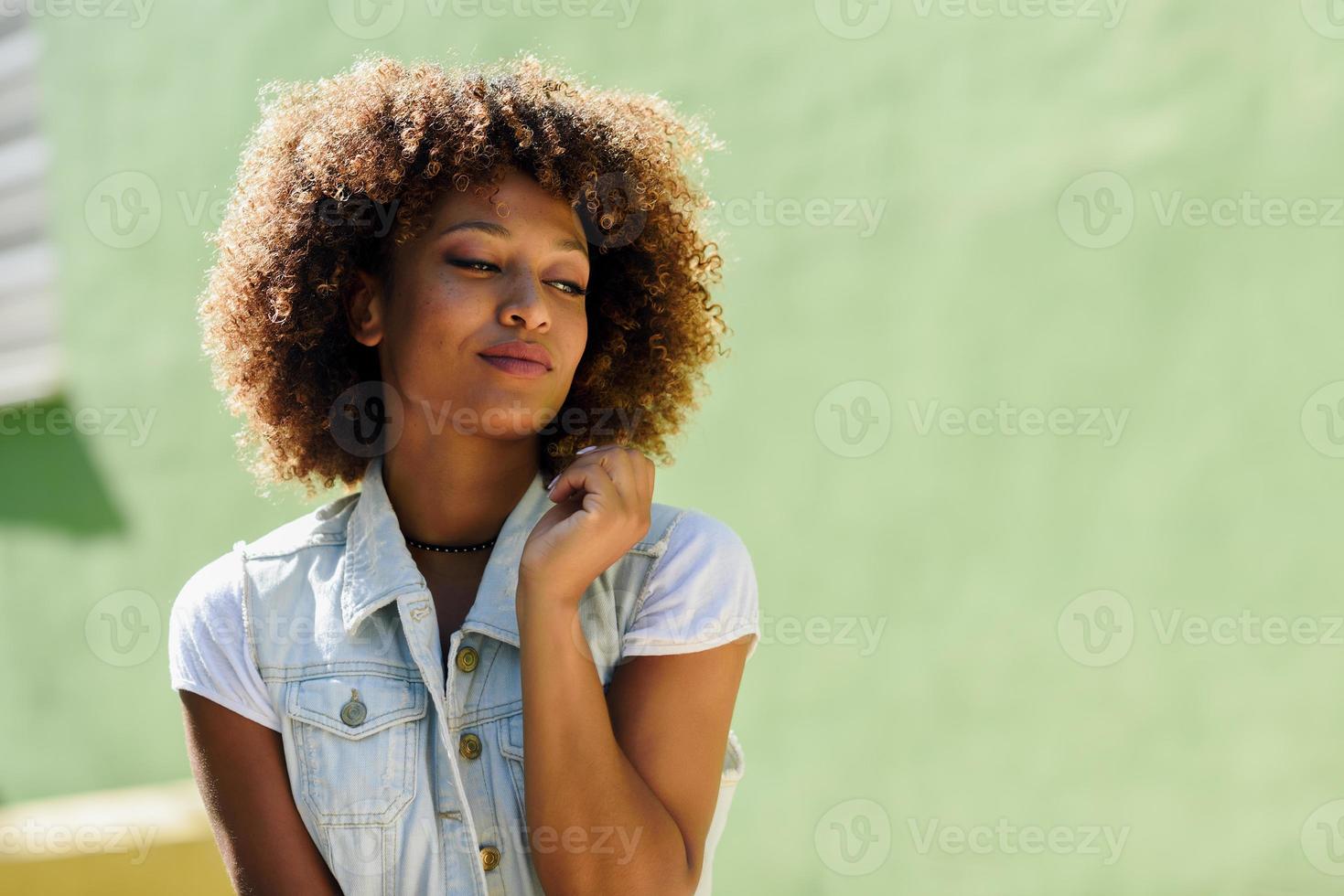 mulher negra, penteado afro, vestindo roupas casuais em meio urbano foto