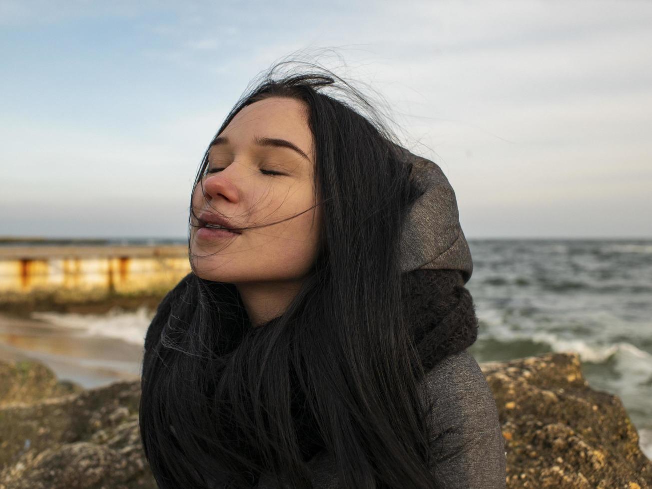 menina sentada em uma pedra perto do mar foto